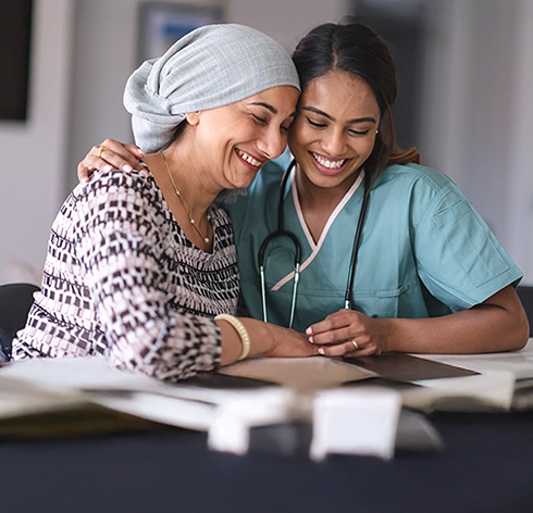 A nurse comforting a smiling woman wearing a headscarf, symbolizing TNBC care and guidance in Canada